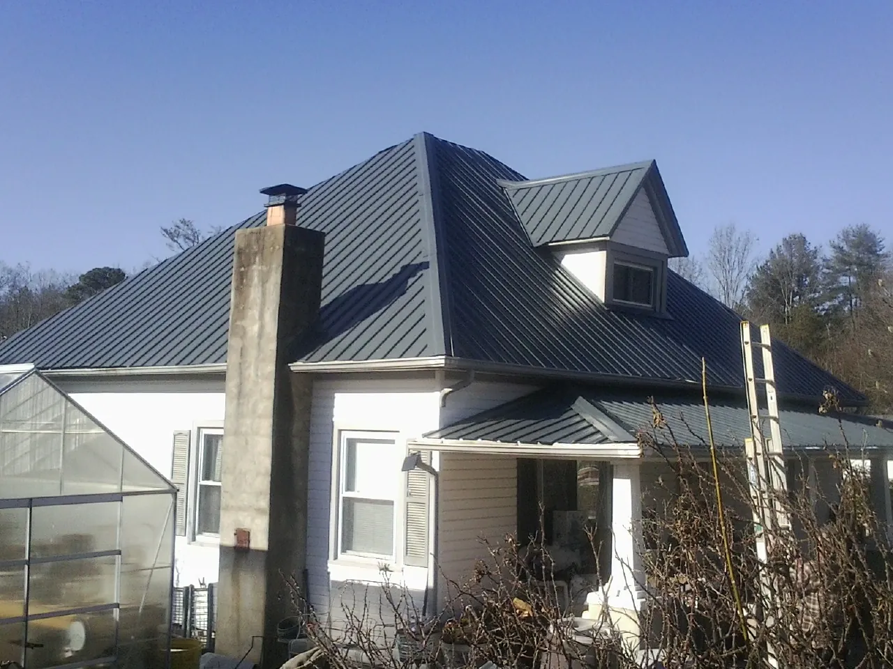 Dark blue standing seam metal roof on a white farmhouse with dormer — Slate & Tile Roof Repair by Roofing Brothers in Currie