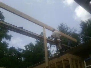 Carpenter setting a ridge beam over a new addition frame — Ice Dam Removal by Roofing Brothers in Currie