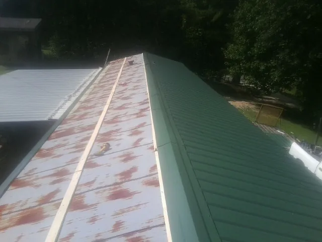 Old rusted panels beside newly installed green metal roofing — Wind Damage Roof Repair by Roofing Brothers in Currie