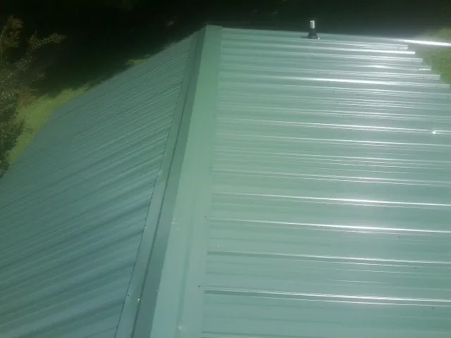 New green metal panels meeting at the ridge of a roof — Flat Roof Repair work by our crew in Currie