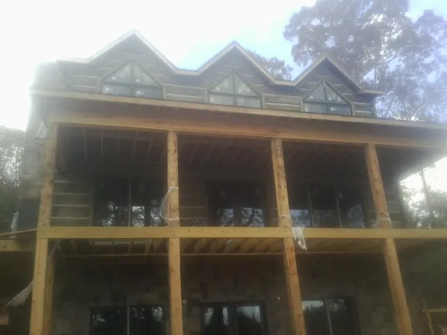 Dormers and porch framing on a large log home under construction — Roof Coating work by our crew in Currie