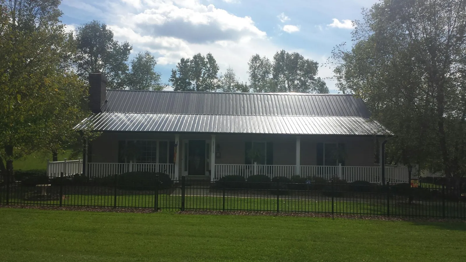 Gray metal roof on a brick ranch with a full width front porch — Gutter Guard Installation work by our crew in Currie